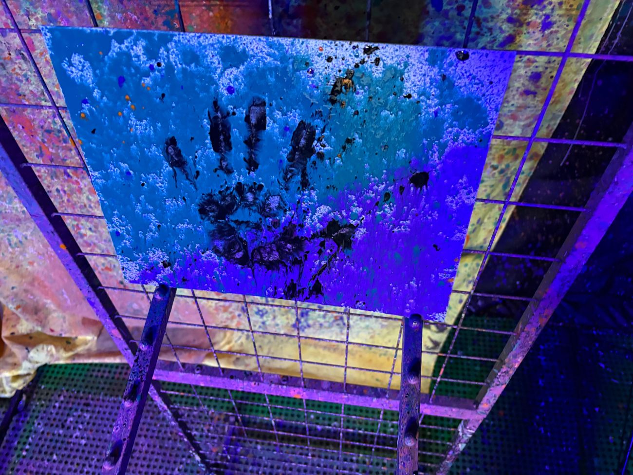 A blue handprint painting under glow lights
